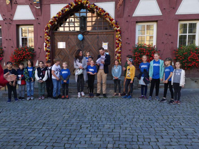 Kinder mit Lehrerin und Bürgermeister vor der Rathaustüre