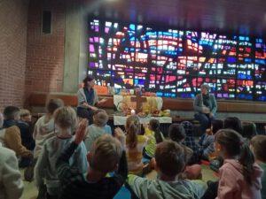 Lehrerinnen und Kinder sitzen um Altar herum