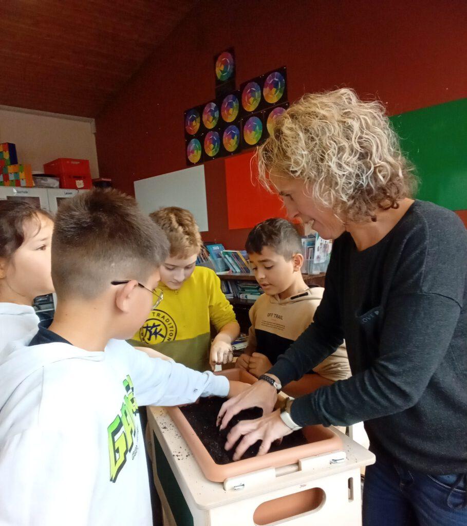 Kinder und Lehrerin stehen um ein Hochbeet