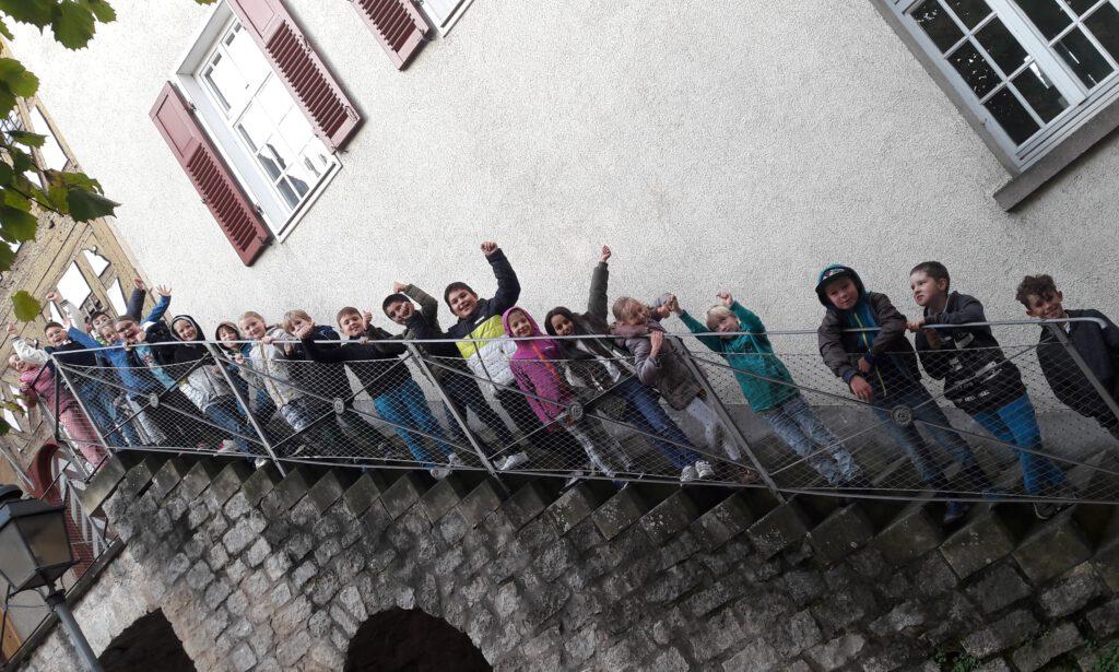 Eine Schulklasse steht auf den Treppenstufen eines Turmes