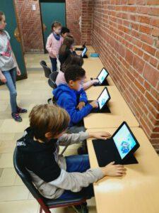 Kinder sitzen an Tablets und arbeiten daran