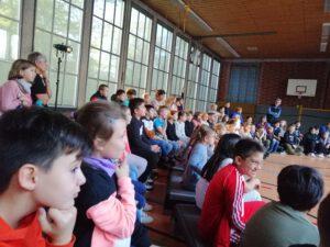 Kinder sitzen in der Turnhalle