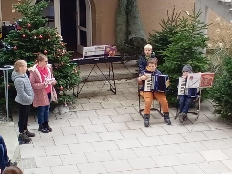 Zwei Kinder mit Instrumenten vor einem Weihnachtsbaum