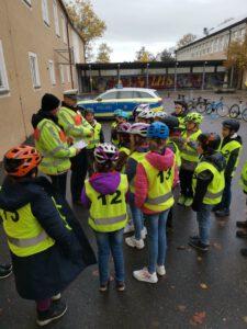 Kinder mit Warnwesten stehen um Polizisten herum auf den Schulhof