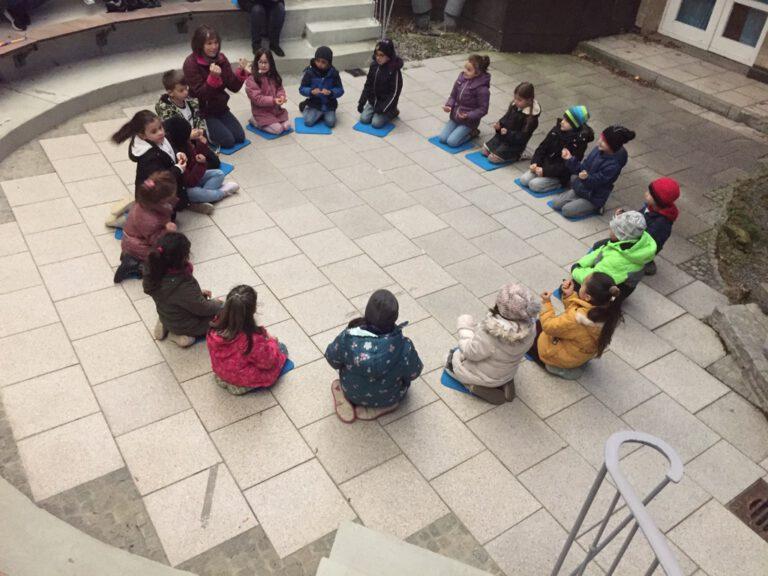 Kinder sitzen im Kreis auf dem Boden